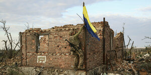 Ein Soldat hisst eine Fahne an einem zerstörten Haus