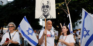 Leute demonstrieren mit einem Pappschild und Israel-Fahnen