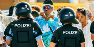 Zwei Polizisten stehen mit dem Rücken zum Betrachter und halten Demonstranten beim Eritrea-Festival in Stuttgart zurück