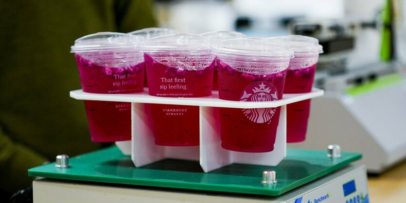 Durchsichtige Plastikbecher mit Starbucks-Logo mit rotem Getränk.