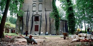 Menschen arbeiten im Freien vor einem alten Backsteingebäude.