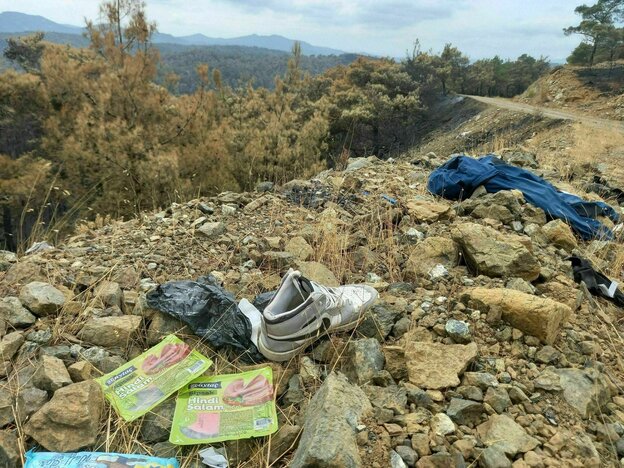 zurückgelassene Schuhe, eine Hose und die Reste einer Salamipacken liegen im Schotter am Rande eines Weges im Nationalpark