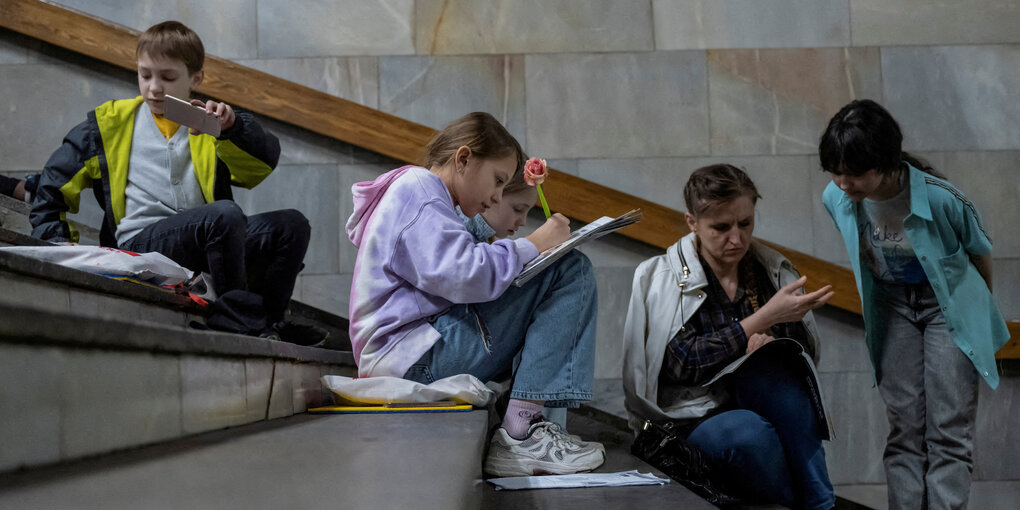 Kinder sitzen auf eine rtreppe und machen Schularbeiten.