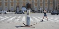 Eine Frau löuft über eine Straße und neben ihr ist eine russiche Rakete aufgestellt.