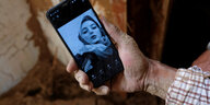 Eine Hand hält ein Handy, das das Bild einer Frau zeigt.