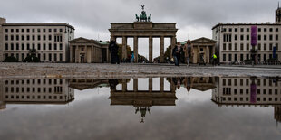 Der Pariser Platz am Brandenburger Tor bei Regenwetter - das Tor spiegelt sich in der Regenpfütze