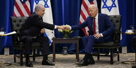Benjamin Netanjahu und Joe Biden sitzen sich gegenüber und reichen sich die Hände