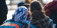 Zwei Mädchen auf dem Weg zur Schule, die eine trägt ein Kopftuch, die andere hat die Haare offen