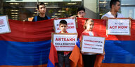 Kinder und Erwachsene zeigen bei einer Demonstration Schilder und die armenische Fahne.