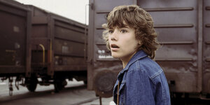 Eine Szene aus der ZDF-Serie Timm Thaler zeigt den jungen Schauspieler Tommi Ohrner vor Güterwaggons.