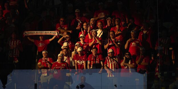 Union-Fans im Estadio Bernabéu in Madrid stehen in der Abendsonne der Gästekurve, alle tragen rote Trikots oder Schals