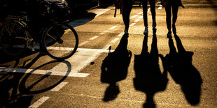 Schatten von Fußgänger:innen an einer Ampel