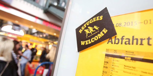 Ein Sticker mit der Botschaft „Refugees Welcome“ auf einer Abfahrttafel der Bahn