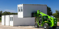 Wohn-Container für Geflüchtete werden von einem Traktor aufgestellt