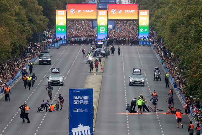 Ak­ti­vis­t:in­nen und Po­li­zis­t:in­nen auf der Laufstrecke kurz vor dem Massenstart beim Marathon in Berlin