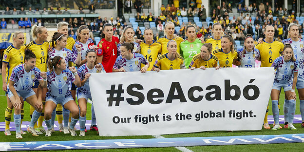 Spaniens und Schwedens Fußballerinnen posieren hinter einem Fransparent mit der Aufaschrift "#SeAcabo"