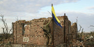 Ein Soldat hisst die ukrainische Flagge in einem rückeroberten Dorf
