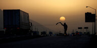 Ein Mann im Sonnenuntergang an einer Autostraße mit vielen Lastern