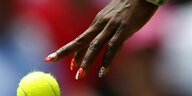 Die Hand einer Tennisspielerin mit langen bunt lackierten Fingernägeln