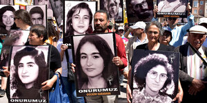 Aktivisten halten Schilder mit Bildern der Opfer hoch