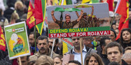 Demonstranten gehen mit Flaggen und einem Schild mit der Aufschrift «Verteidigt Rojava! Steht auf für Rojava!