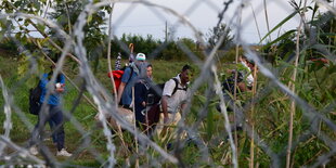 Menschen auf der anderen Seite des Grenzzaunes