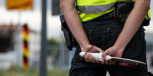 Ein Polizist von hinten mit einer Weste und einer Haltekelle in der Hand