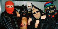 Vier Männer in schwarzen Jacken und eine Frau - natürlich im sexy Bikinioberteil, tragen bunte Sturmhauben, Masken über Kopf, sind aber bester Stimmung