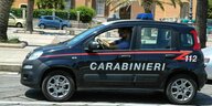 Ein kleiner Fiat mit der Aufschrift Carabiniere unterwegs auf Sardinien, Palmen im Hintergrund