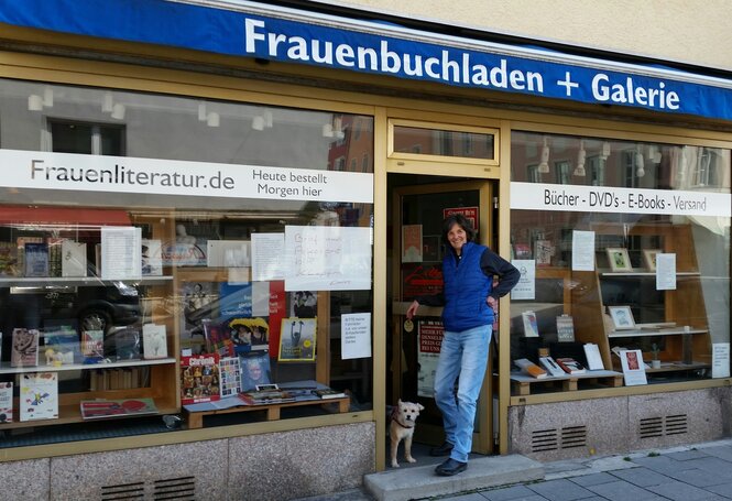 An­drea Gollbach steht in der Tür zu ihrem Buchladen zusammen mit Hund