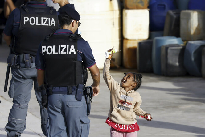 Ein kleines Mädchen spielt mit einer Polizisten mit Seifenblasen