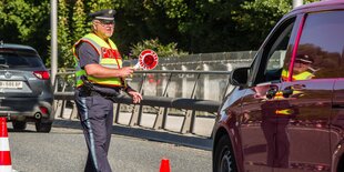 Polizist kontrolliert ein rotes Auto.