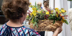 Eine Frau, die von hinten zu sehen ist, trägt ein buntes Blumengestek