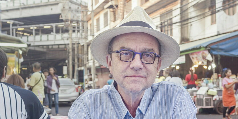 Porträt von Willi Germund, er sitzt an einem Tisch in einem Cafe in Bangkok