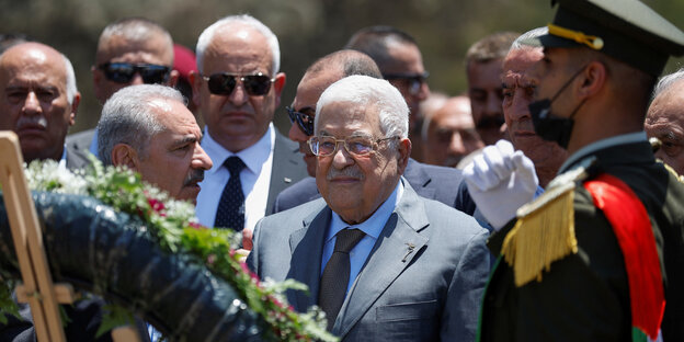Mahmoud Abbassteht vor einem aufgehängten Kranz in Dschenin, umringt von Männern mit ernstem Gesichtsausdruck