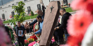 Männer heben den Sargdeckel hoch bei einer Beerdigung auf dem Friedhof