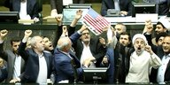 Iran, Teheran: Als Protest gegen den Ausstieg der USA aus dem internationalen Atomabkommen verbrennen Abgeordnete im iranischen Parlament zwei Stücke Papier. Das eine zeigt die amerikanische Flagge, das andere soll eine symbolische Kopie des Atomabkommens