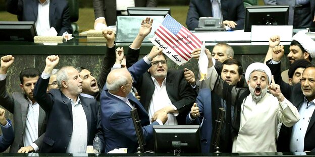 Iran, Teheran: Als Protest gegen den Ausstieg der USA aus dem internationalen Atomabkommen verbrennen Abgeordnete im iranischen Parlament zwei Stücke Papier. Das eine zeigt die amerikanische Flagge, das andere soll eine symbolische Kopie des Atomabkommens sein