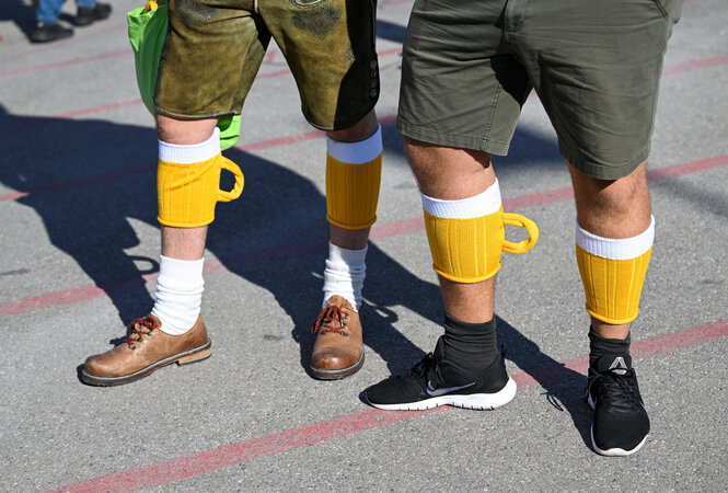 Die Waden von zwei Männern zeigen Strümpfe in Bierkrugform – zwei von sechs Millionen Besucher:innen des Oktoberfestes