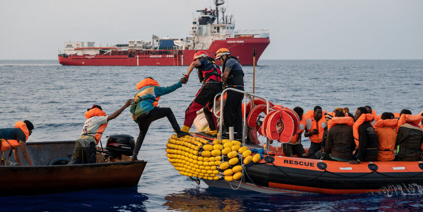 Menschen steigen auf dem Meer von einem Boot in ein anderes