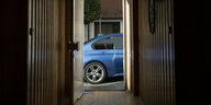 Aus einem Hausflur lässt sich durch die offene Tür das Heck eines BMWs erkennen