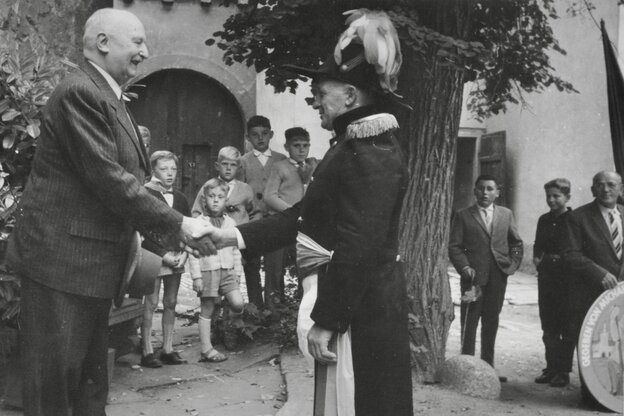 Schwarz-weiß Aufnahme der Kirchweih 1961 in Sommerhausen. Zwei Dorfhonorationen geben sich die Hand, eine Gruppe Kinder schaut zu.