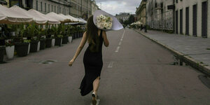 Eine Frau mit einem Blumenstrauß läuft eine Straße entlang