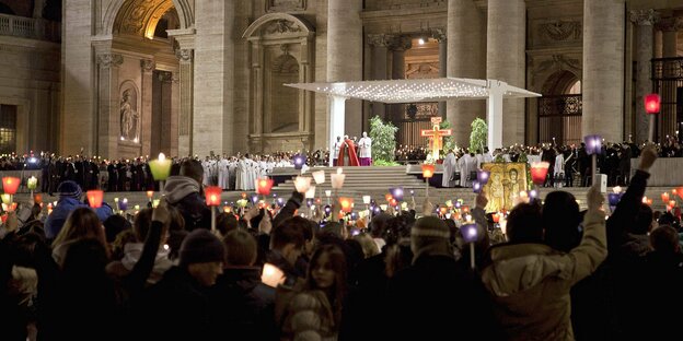 Jugendliche halten auf dem Petersplatz in Rom Kerzen in die Höhe. Im Hintergrund sind die Brüder von Taizé und Papst Benedikt XVI. zu sehen.