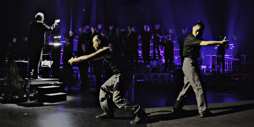 In der "Tischlerei" in der Deutschen Oper: 2 Tänzer und ein Chor samt Dirigent sind für eine experimentelle Oper zusammen auf der Bühne