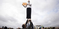Eine Demonstrantin mit Plakat "There Is No Planet B " wird von anderen Demonstranten in die Luft gehoben, im Hintergrund das Kanzleramt in Berlin