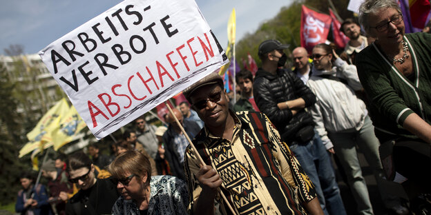 Demonstrant mit Plakat "Arbeitsverbote Abschaffen" auf der 1. Mai-Demo in Berlin