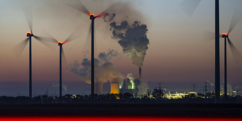 Windräder vor Kohlekraftwerk in der Dämmerung