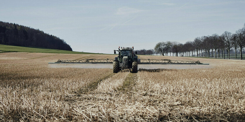 Ein Traktor fährt über ein Feld und bringt Glyphosat aus.