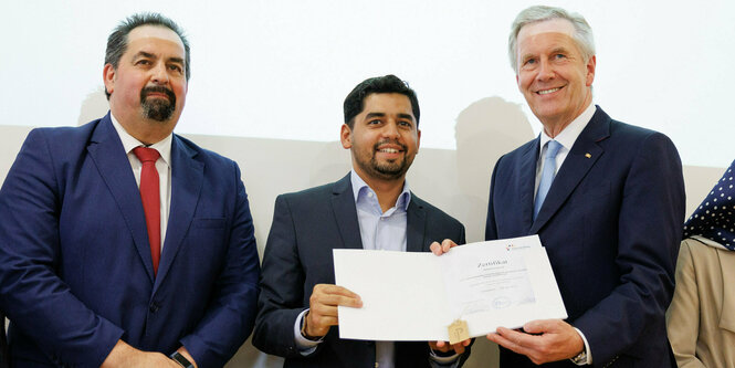 Christian Wulff (r), Bundespräsident a.D., überreicht Absolvent Muhamed Memedi (M) das Zertifikat bei der Abschlussfeier für die ersten Absolventen der Imam-Ausbildung. Aiman Mazyek, Vorsitzender des Zentralrats der Muslime in Deutschland,